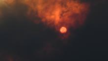 The sun is seen through heavy smoke as a bushfire burns in Woodford.