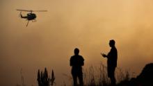 Forster residents watch as a water-bombing helicopter flies over a bushfire on November 7.