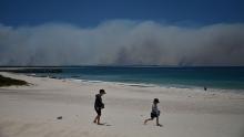 Fires burn in the distance as children play on a beach in Forster on November 9.