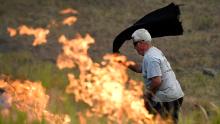 A man uses a wet towel to help put out flames near the town of Taree on November 14.