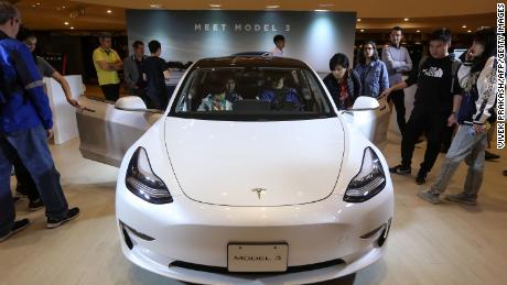 People look at a Tesla Model 3 displayed at a shopping mall in Hong Kong on March 10, 2019. 