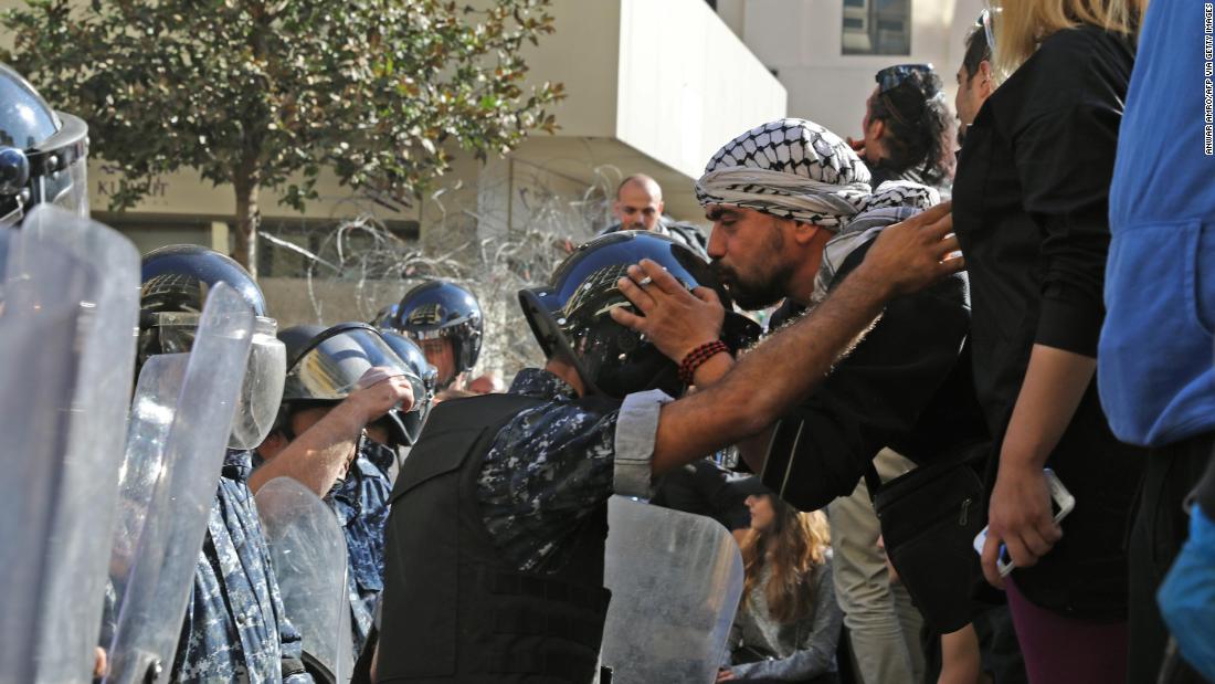 A Lebanese protester kisses the helmet of a riot policeman on November 19 near the parliament headquarters in Beirut.