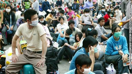 Wanderarbeiter in Gesichtsmasken warten vor dem Bahnhof in Guangzhou, China, bevor sie während des SARS-Ausbruchs 2003 nach Hause zurückkehren.