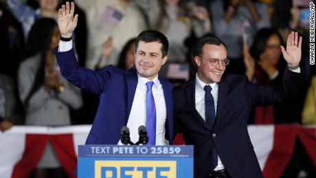 Pete Buttigieg and his husband Chasten, right, wave to supporters at a caucus night campaign rally, Monday, February 3 in Des Moines, Iowa.