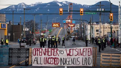 Polizisten stehen auf einer Straße, nachdem sie die Kreuzung von Demonstranten geräumt haben, die am Mittwoch in Vancouver, British Columbia, die Einfahrt zu einem Hafen blockierten. Die Demonstration drückte ihre Solidarität mit den Demonstranten aus, die letzte Woche festgenommen wurden.