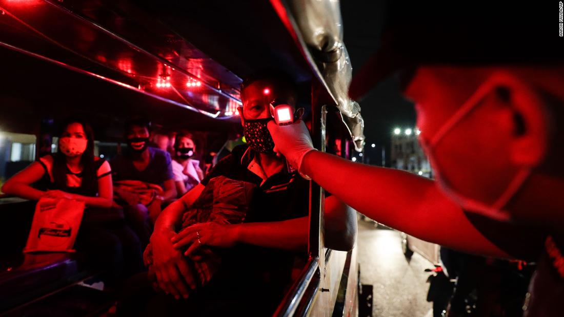 A police officer checks the temperatures of bus passengers at a checkpoint in Manila, 菲律宾, 在三月 16.