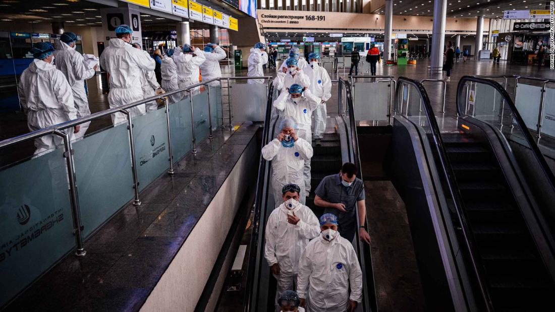 Medical staff wearing protective suits ride down an escalator at Moscow&#39;s Sheremetyevo International Airport on March 18.