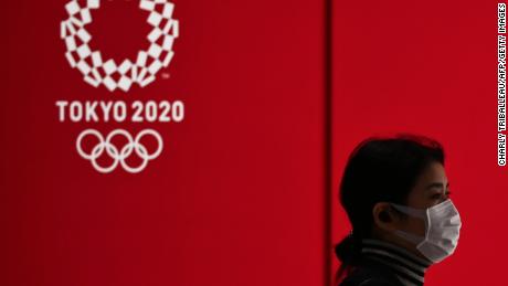 Eine Frau in einer Gesichtsmaske geht an einer Anzeige vorbei, die das Logo der Olympischen Spiele Tokio 2020 in Tokio am 24. März 2020 zeigt.