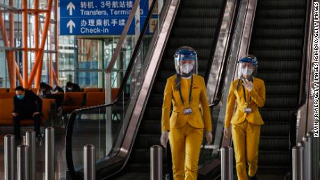 Die Mitarbeiter tragen Schutzmasken und Visiere, wenn sie am 24. März im Ankunftsbereich des internationalen Flughafens Beijing Capital spazieren.