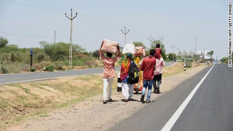 Wanderarbeiter und ihre Familienmitglieder gehen eine Autobahn entlang, um verzweifelt in ihr Dorf zurückzukehren.