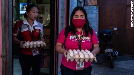 Rosalie Natividad wears a makeshift mask as she carries eggs to local families.