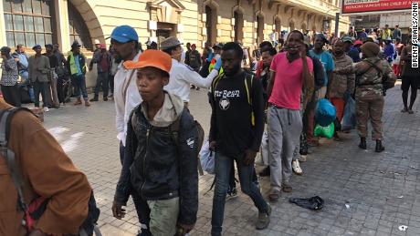 Linien obdachloser Südafrikaner warten auf den Transport der Polizei zu Notunterkünften in der Innenstadt von Johannesburg.