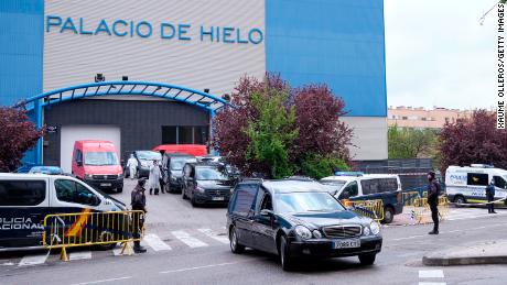 Bestattungsautos und Lieferwagen warten in Madrid vor einer Eisbahn, die vorübergehend in eine Leichenhalle umgewandelt wurde, in der Hunderte von Leichen untergebracht sind.