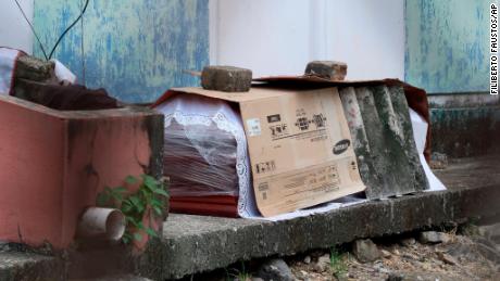 Ein Sarg mit der Leiche einer Person, die an Covid-19 gestorben sein soll, liegt am 2. April vor einem Wohnblock in Guayaquil in Plastik eingewickelt und mit Pappe bedeckt.