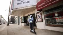 بیورلی ہلز ، کیلیفورنیا میں 18 مارچ 2020 کو ایک بند فلمی تھیٹر کے پاس اسکوٹر پر سوار ہوتے ہوئے ایک شخص اپنے چہرے پر دستانے اور بینڈنا پہنتا ہے۔ 