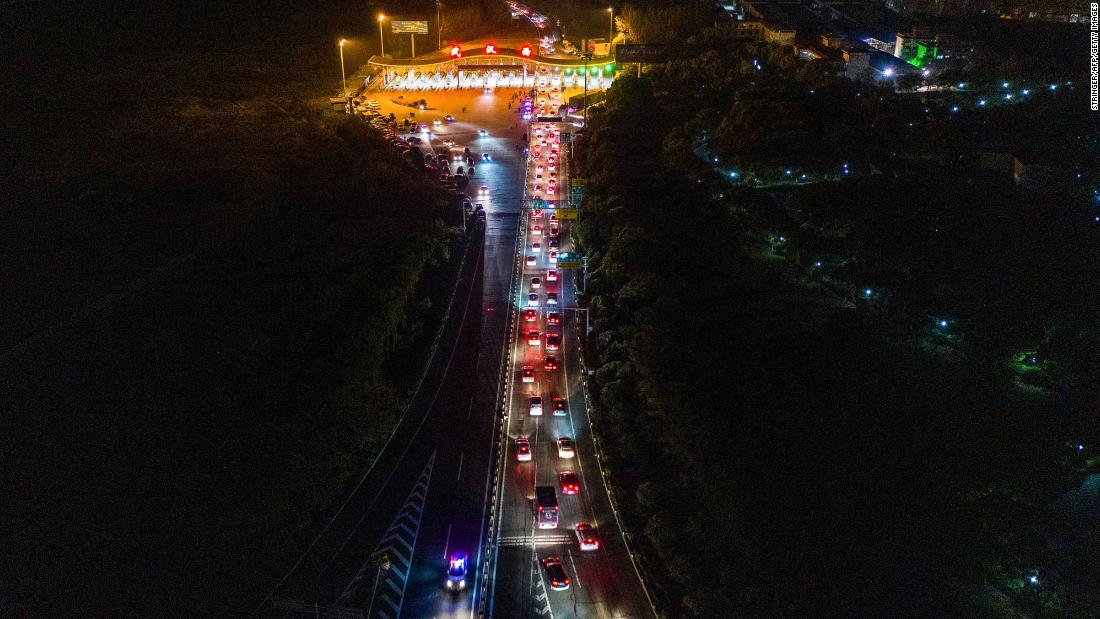 Cars in Wuhan line up to leave at a highway toll station.