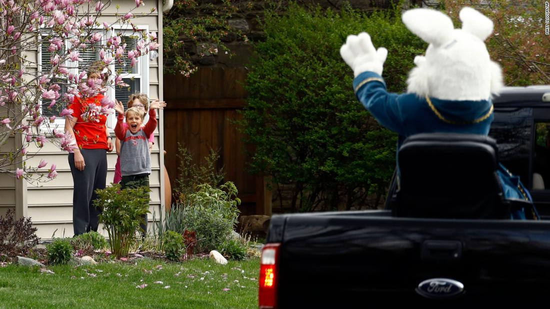 Children wave to a person dressed as the Easter Bunny during a neighborhood parade in Haverford, 宾夕法尼亚州, 在四月 10.
