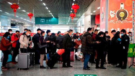 Passagiere in Gesichtsmasken, die anstehen, um einen grünen QR-Code auf ihren Telefonen zur Sicherheit bei der Ankunft am Bahnhof Wenzhou in Wenzhou anzuzeigen.