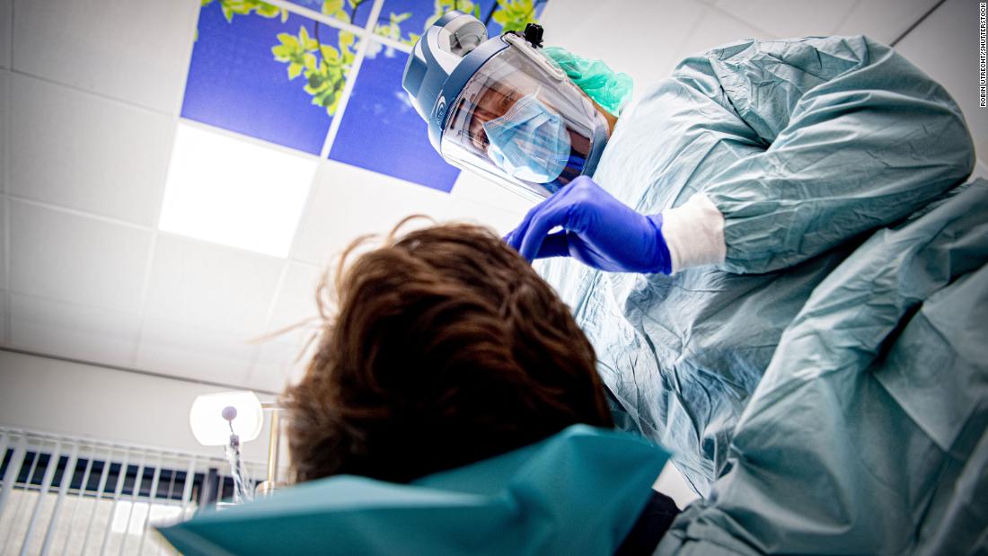 A dentist wears protective equipment while treating a patient in Den Bosch, オランダ, 四月に 22.