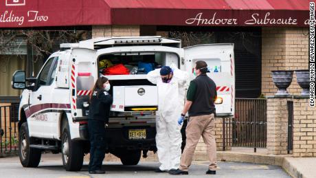 Medical workers put on masks and personal protective equipment while preparing to transport a body at Andover Subacute and Rehabilitation Center on April 16, 2020 in Andover, New Jersey. (Eduardo Munoz Alvarez/Getty Images)