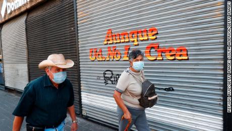 People walk by a closed store during the pandemic in Guadalajara City,  Mexico.