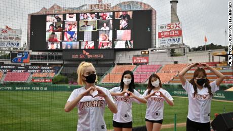 Cheerleader posieren vor einer großen Leinwand und zeigen Baseballfans, die während des Eröffnungsspiels der neuen Baseball-Saison Südkoreas zwischen den SK Wyverns und Hanwha Eagles am Dienstag im Munhak Baseball Stadium in Incheon von zu Hause aus jubeln.