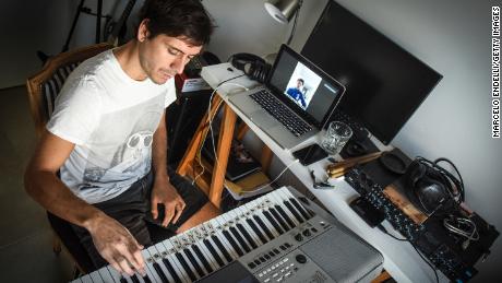 Der Musiker Tati Diaz Bonilla spielt auf der Tastatur, während ein Student während einer Online-Lektion in seiner Wohnung in Buenos Aires, Argentinien, Zoom hört und beobachtet. (Marcelo Endelli / Getty Images)