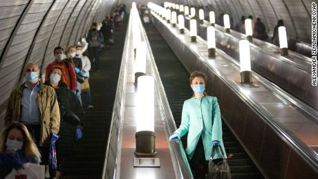 Menschen mit Gesichtsmasken und Handschuhen auf einer U-Bahn-Rolltreppe in Moskau am Dienstag.