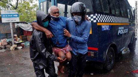 Polizisten bringen einen behinderten Mann nach seiner Evakuierung aus einem Slumgebiet in Kolkata, Indien, an einen sichereren Ort.
