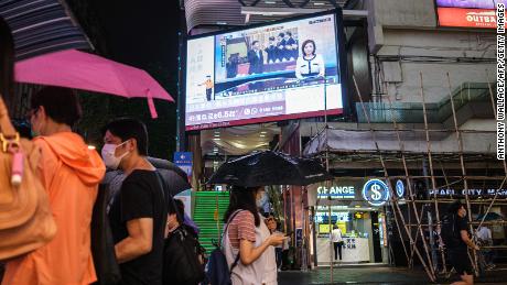 Fußgänger gehen am 21. Mai 2020 in Hongkong unter einen Fernsehbildschirm und zeigen eine Nachrichtensendung von Filmmaterial aus Peking des chinesischen Präsidenten Xi Jinping (C) auf der politischen Konsultativkonferenz des chinesischen Volkes.