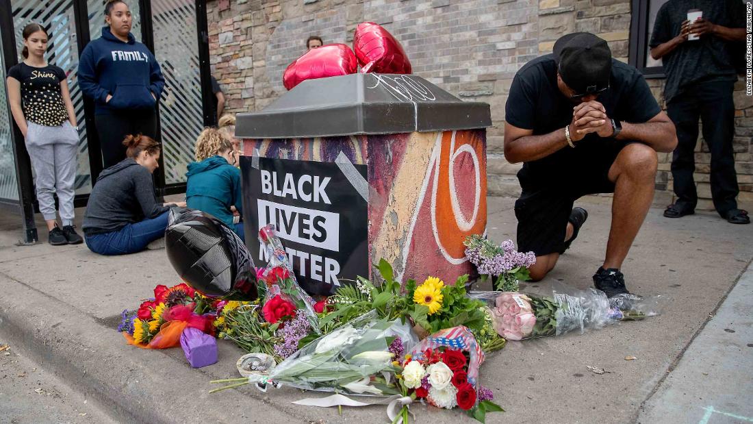 People gather and pray around a makeshift memorial in Minneapolis on May 26. It was near the site where Floyd was taken into police custody the previous day.