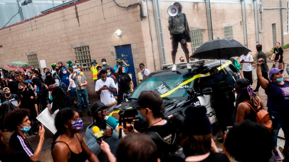 Protesters rally around a damaged police vehicle in Minneapolis on May 26.