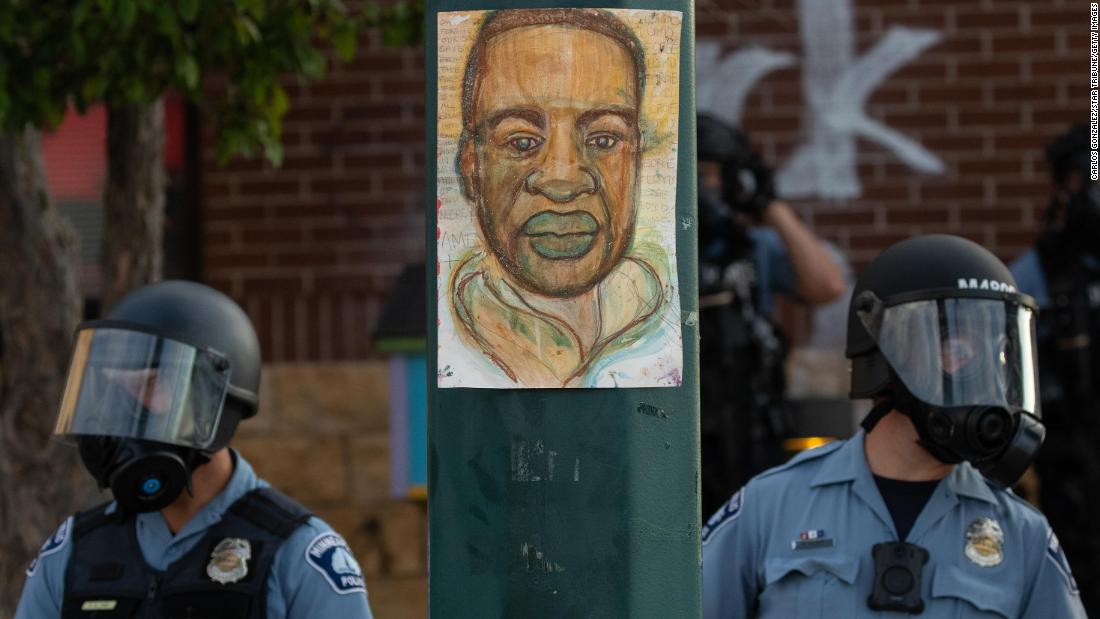 Minneapolis police stand by an illustration of Floyd as demonstrators rally on May 27.