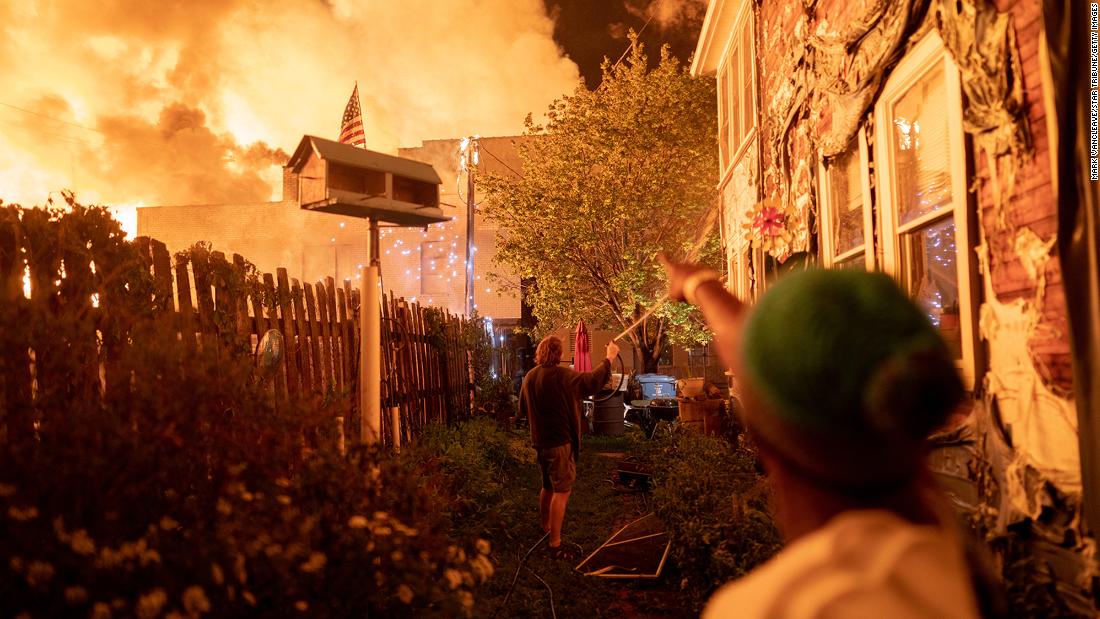 People use garden hoses and buckets to save homes in Minneapolis after rioters set fire to a housing complex under construction on May 27.