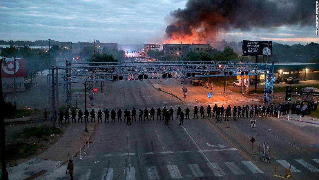 Police gather along Minneapolis&#39; Lake Street early on May 29 as fires burned after a night of unrest.