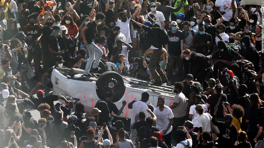 Protesters jump on an overturned car near the Municipal Services Building in Philadelphia on May 30.