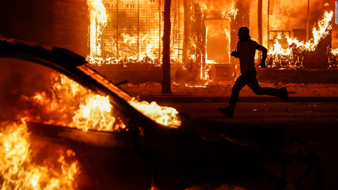 A protester runs past burning cars and buildings in St. Paul on May 30.