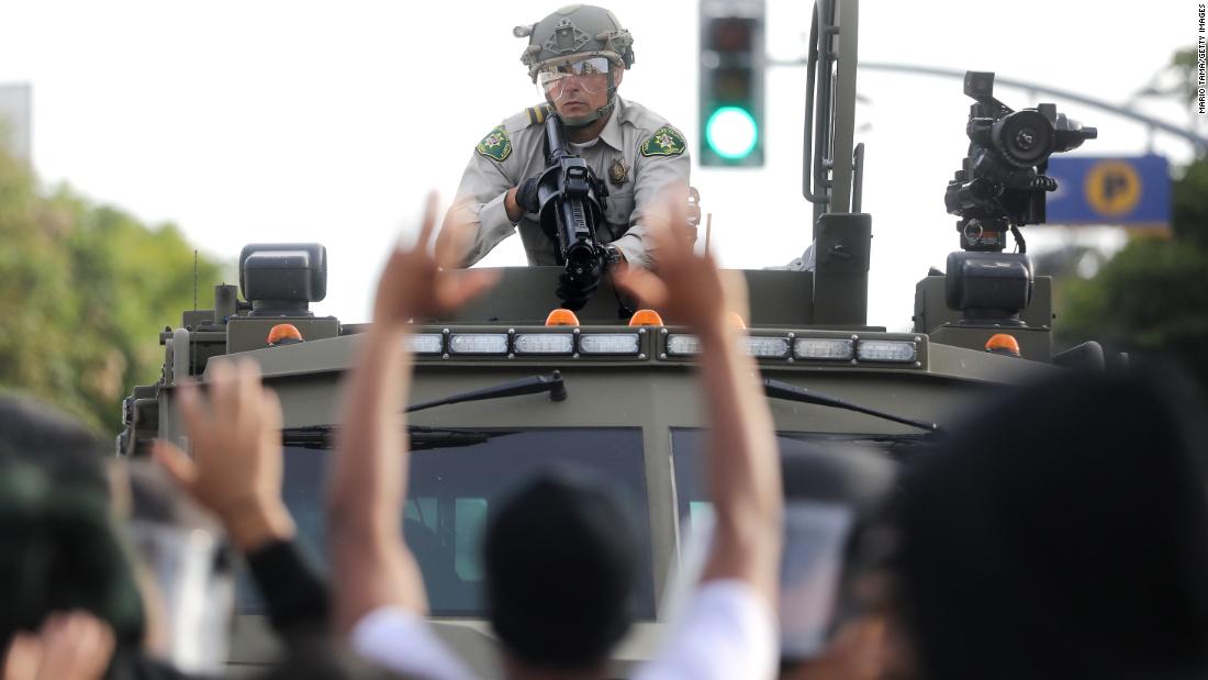 A police officer aims a nonlethal weapon as protesters raise their hands in Santa Monica, Kalifornië, op Mei 31.