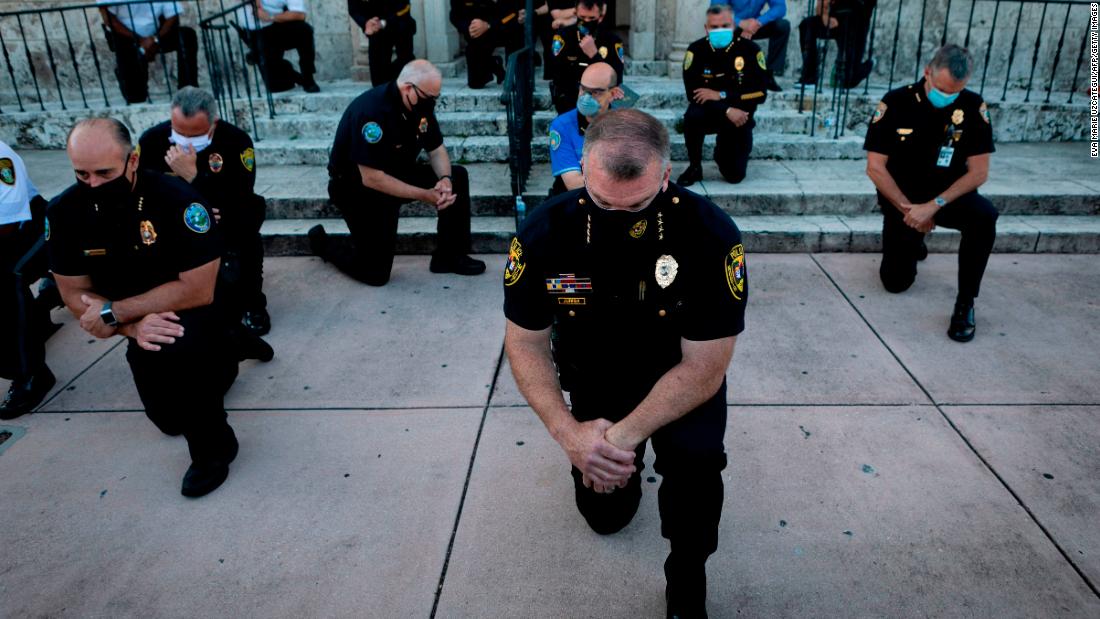 Police officers kneel during a rally in Coral Gables, Florida on May 30,.