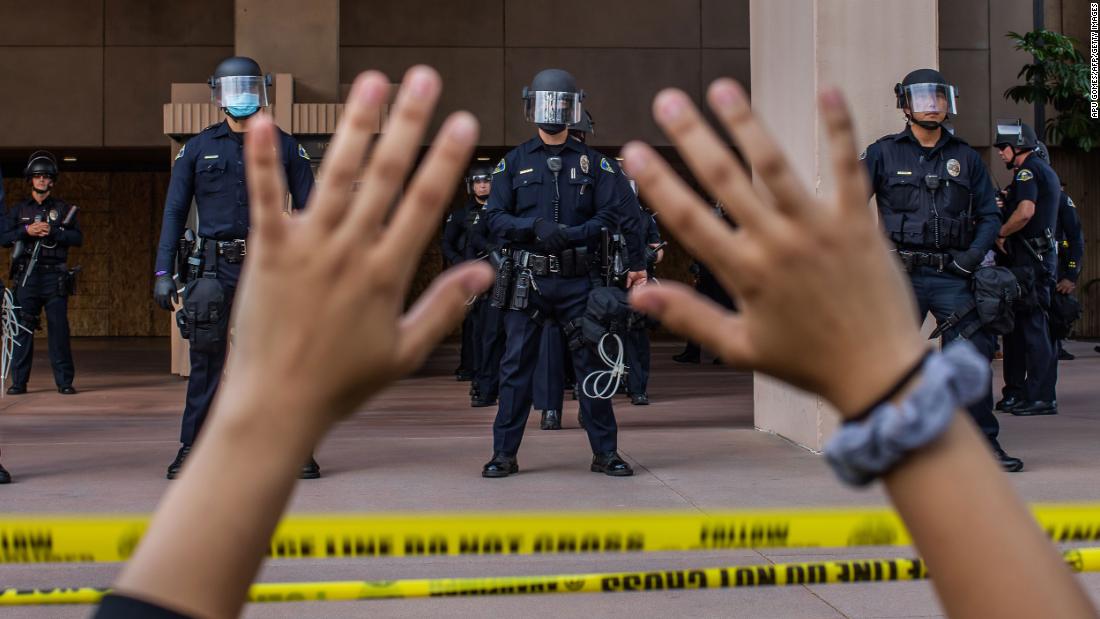 A demonstrator holds her hands up while she kneels in front of police officers at City Hall in Anaheim, 加利福尼亚州, 在六月 1.