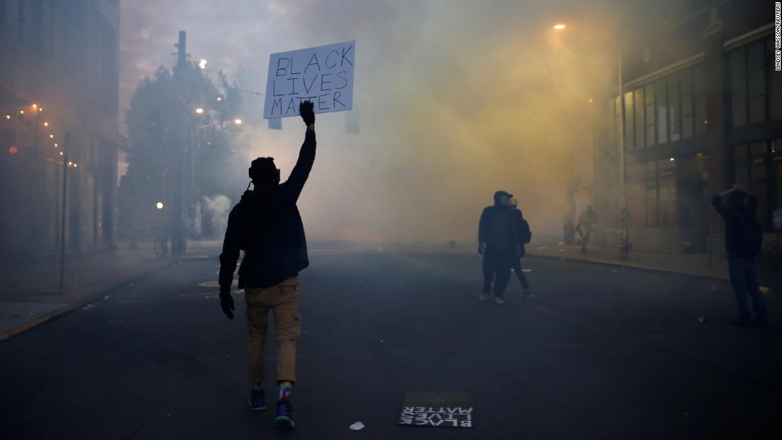 A person holds a &quot;검은 생명의 문제인용;quot; sign as a heavy cloud of tear gas and smoke rises in Seattle on June 1.