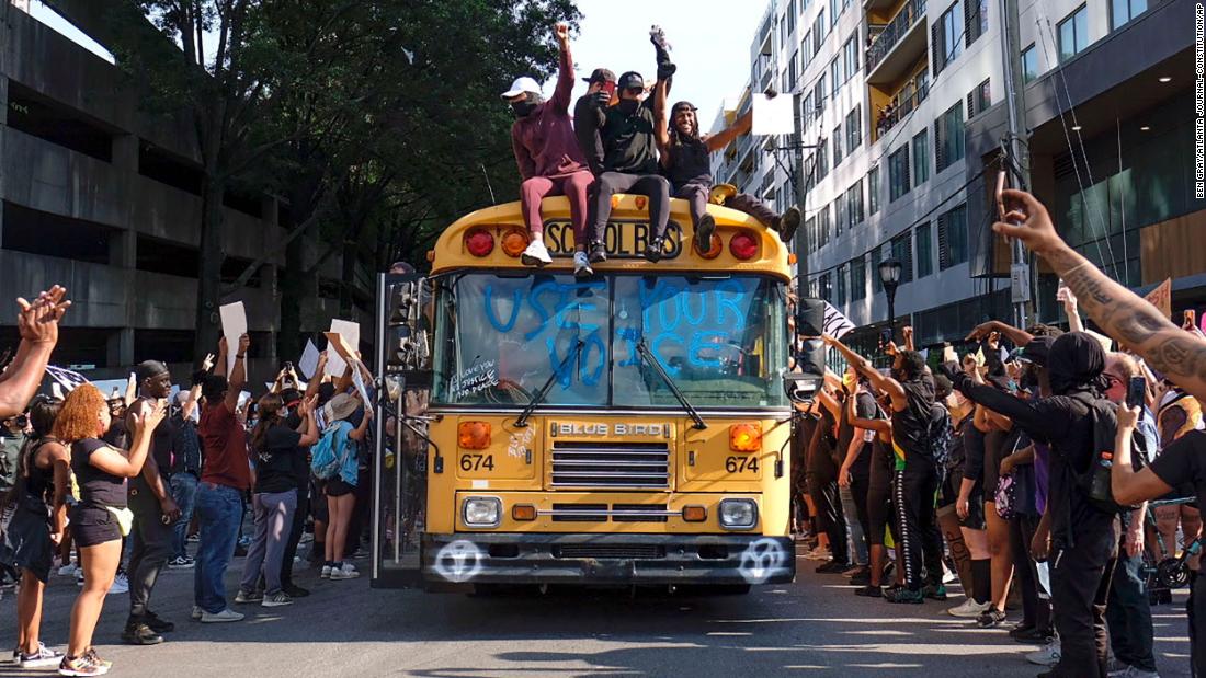 Protesters ride a bus through a street in Atlanta on June 2. The windshield reads &quot;use your voice.&报价;