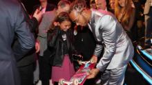 Brown shows her skateboard to British F1 driver Lewis Hamilton after the 2020 Laureus World Sports Awards.