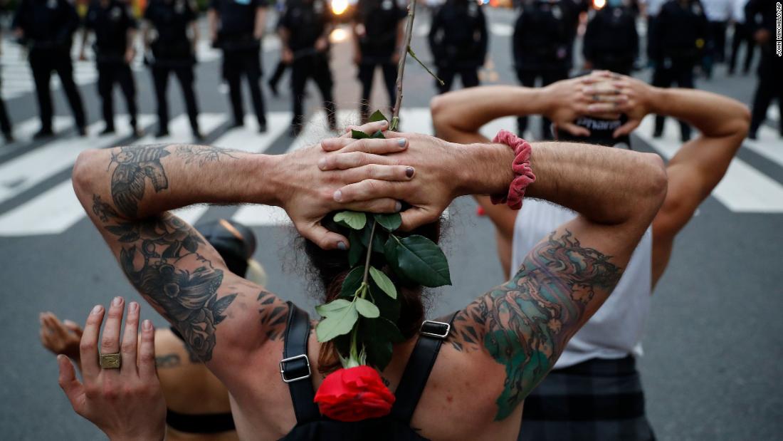 Protesters kneel in front of New York City police officers before being arrested for violating curfew on June 3.
