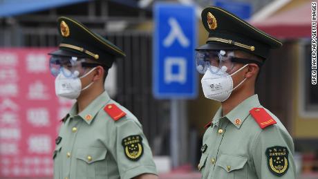   Los agentes de la policía paramilitar usan máscaras faciales y gafas protectoras cuando hacen guardia en la entrada del mercado cerrado de Xinfadi en Beijing el 13 de junio. 