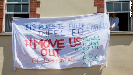 Asylsuchende im Skellig Star halten ein Banner, das gegen die Behandlung des Covid-19-Ausbruchs am 7. Mai protestiert.