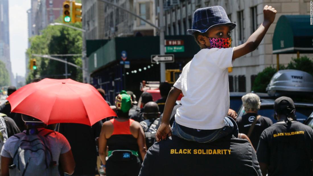 A man marches with a child on his shoulders during a Juneteenth celebration in New York.