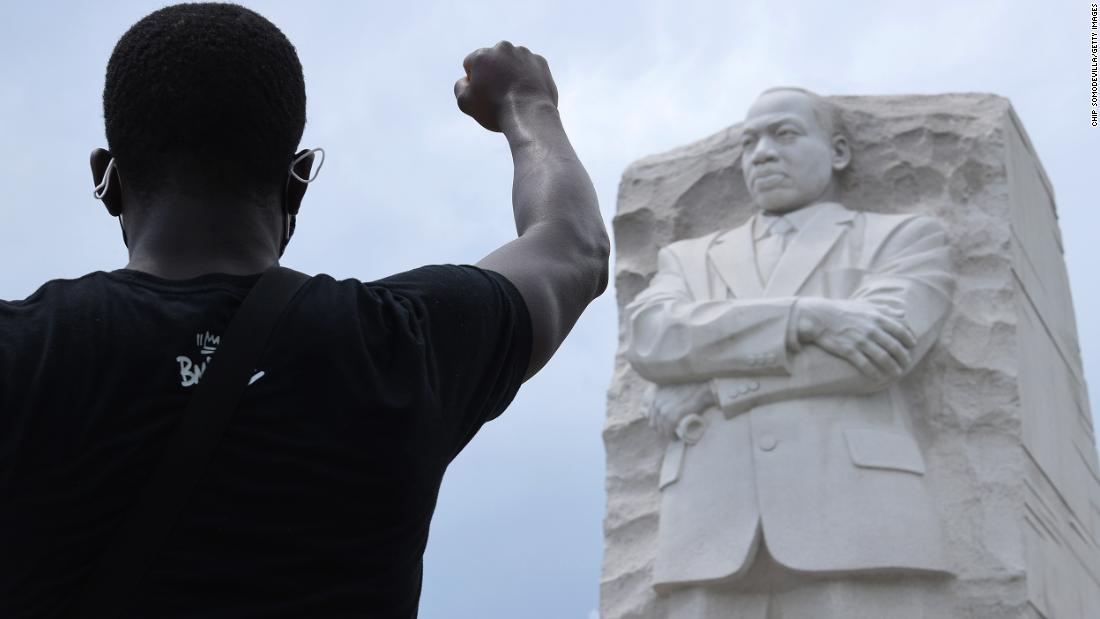 A man kneels and raises his fist in the air at the Martin Luther King Jr. Memorial in Washington, DC, 6 월 19.