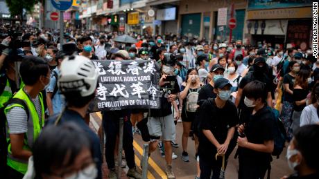 Passers-by and protesters gather in Causeway Bay, Hong Kong. A protester is seen carrying a flag that says &quot;Liberate Hong Kong, revolution of our times,&quot; an act that could now be considered a crime under the city&#39;s new national security law.