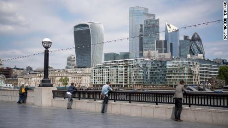 Die Menschen beobachten soziale Distanzierung, wenn sie am 9. Juni auf die Skyline des Londoner Finanzviertels blicken.